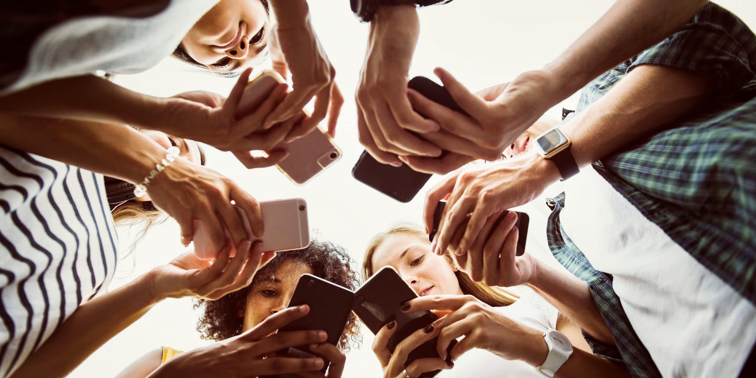 group of teens on their mobile phones standing in a circle