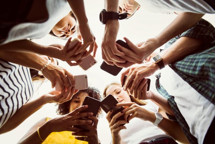 group of teens on their mobile phones standing in a circle